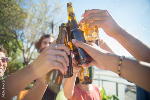 Photography Close-up of content friends clinking beer bottles and glasses