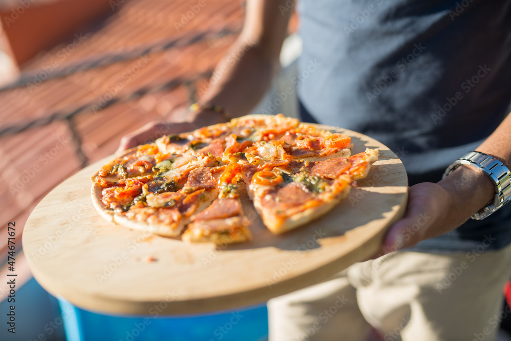 Close-up of sliced pizza on plate. Man in black T-shirt holding pizza. Snack, food, party concept