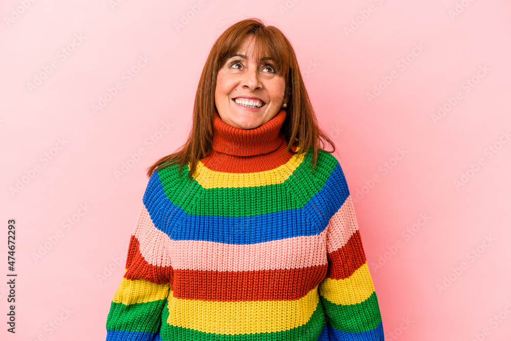 Middle age caucasian woman wearing a multicolor sweater isolated on pink background dreaming of achieving goals and purposes Middle age caucasian woman wearing a multicolor sweater isolated on pink background dreaming of achieving goals and purposes