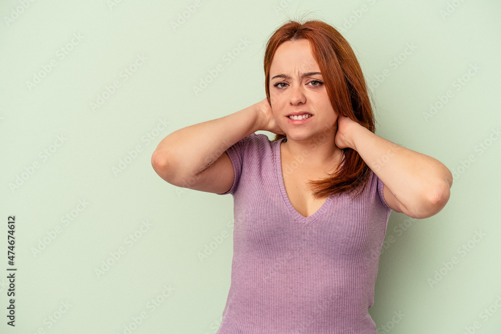 Young caucasian woman isolated on green background touching back of head, thinking and making a choice. Young caucasian woman isolated on green background touching back of head, thinking and making a choice.
