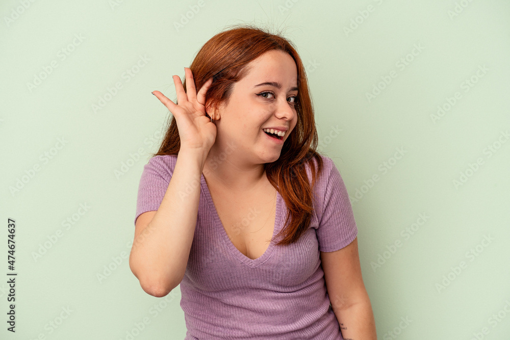 Young caucasian woman isolated on green background trying to listening a gossip. Young caucasian woman isolated on green background trying to listening a gossip.