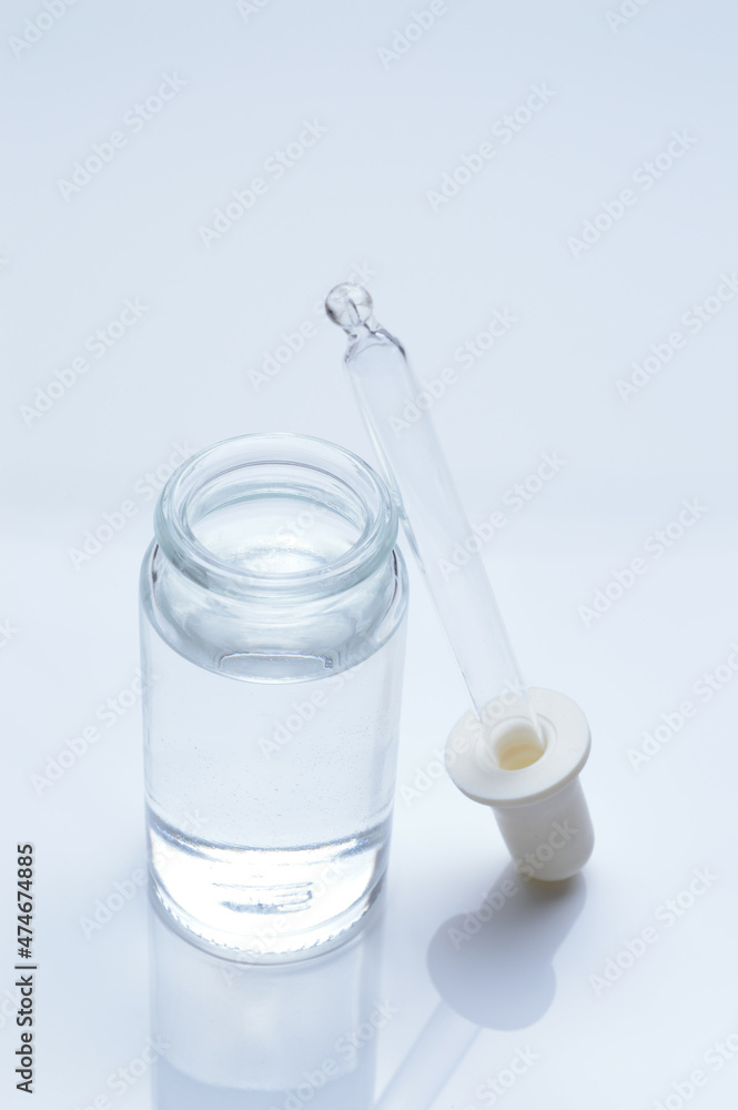 glass transparent jar and a cosmetic pipette with liquid droplets on a white background. glass transparent jar and a cosmetic pipette with liquid droplets on a white background.
