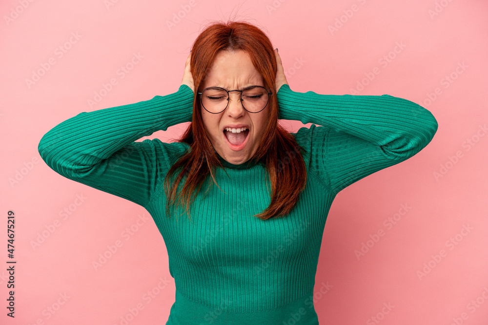 Young caucasian woman isolated on pink background covering ears with hands trying not to hear too loud sound. Young caucasian woman isolated on pink background covering ears with hands trying not to hear too loud sound.