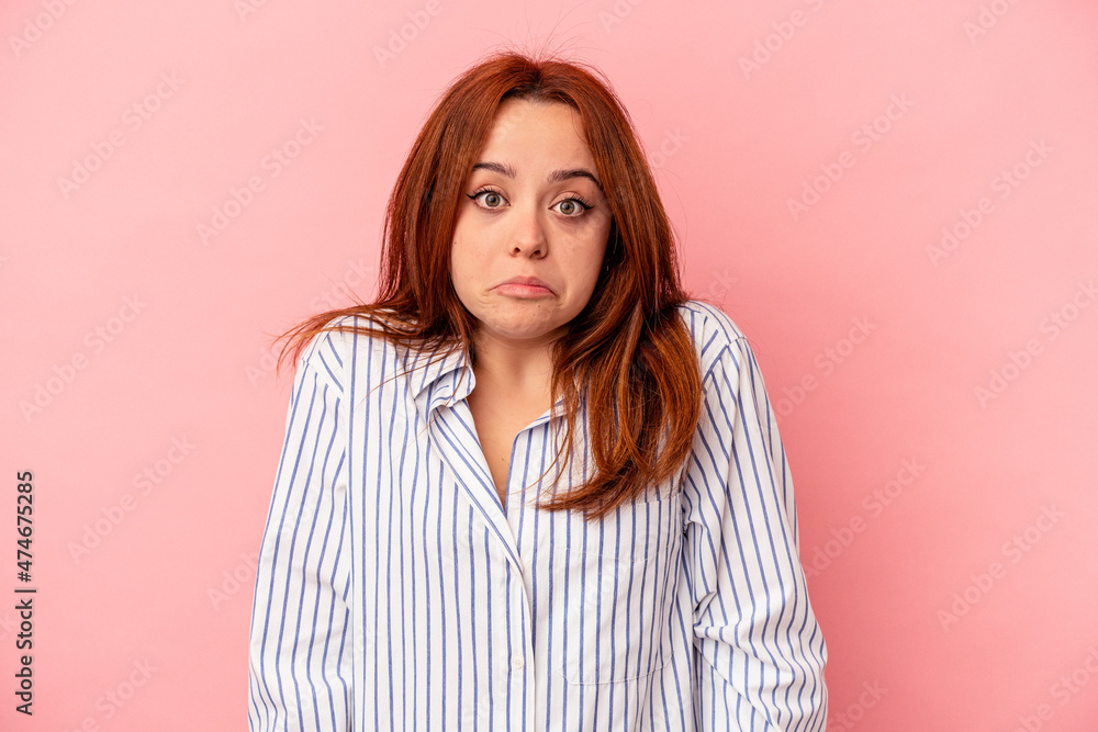 Young caucasian woman isolated on pink background shrugs shoulders and open eyes confused. Young caucasian woman isolated on pink background shrugs shoulders and open eyes confused.