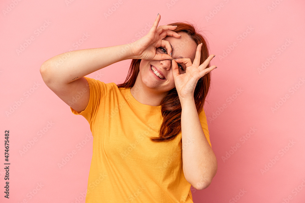 Young caucasian woman isolated on pink background showing okay sign over eyes Young caucasian woman isolated on pink background showing okay sign over eyes