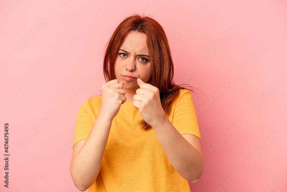 Young caucasian woman isolated on pink background showing fist to camera, aggressive facial expression. Young caucasian woman isolated on pink background showing fist to camera, aggressive facial expression.
