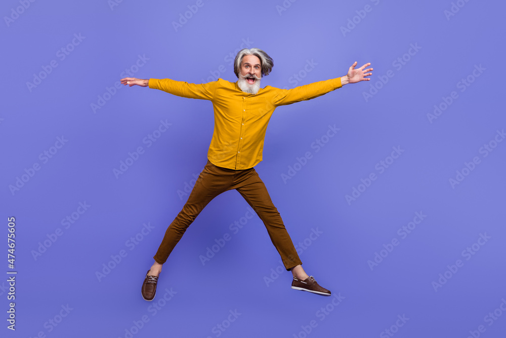 Full length body size view of attractive cheery funny gray-haired man jumping having fun isolated over bright violet purple color background Full length body size view of attractive cheery funny gray-haired man jumping having fun isolated over bright violet purple color background