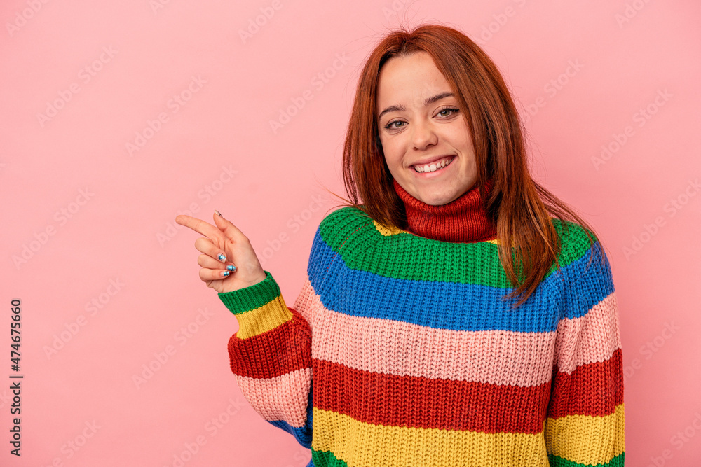 Young caucasian woman isolated on pink background smiling cheerfully pointing with forefinger away.