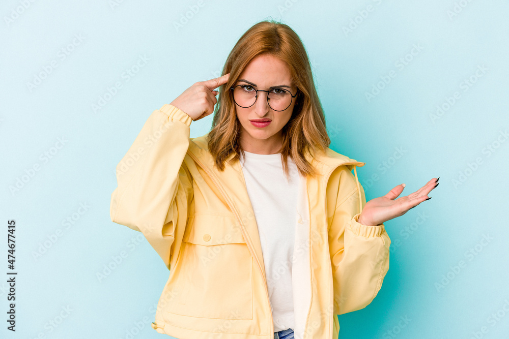 Young caucasian woman isolated on blue background showing a disappointment gesture with forefinger. Young caucasian woman isolated on blue background showing a disappointment gesture with forefinger.