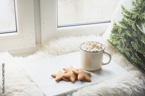Winter coffee with cookies as stars on cozy window sill with Christmas evergreen natural fir branches.