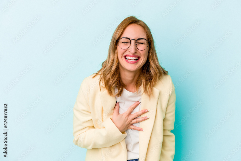 Fototapeta premium Young caucasian woman isolated on blue background laughs out loudly keeping hand on chest.