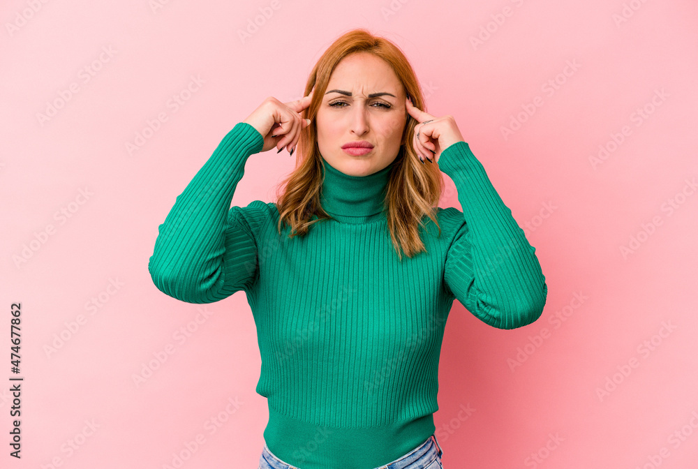 Fototapeta premium Young caucasian woman isolated on pink background focused on a task, keeping forefingers pointing head.