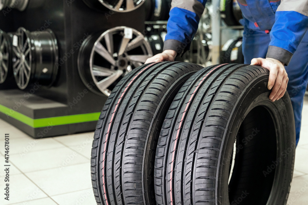 Fototapeta premium the seller rolls a pair of new tires for the season to the store's exit. buying new wheels - road safety
