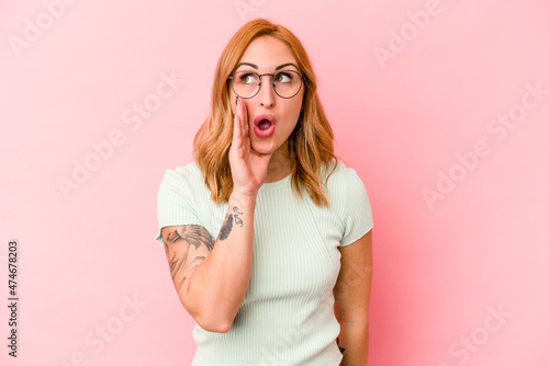 Young caucasian woman isolated on pink background shouting excited to front.