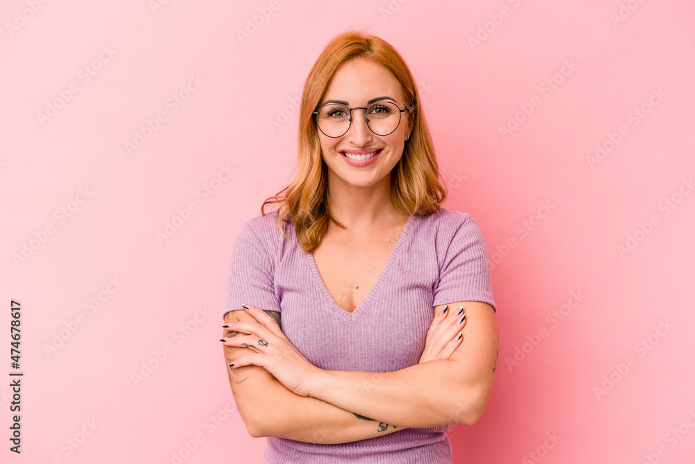 Young caucasian woman isolated on pink background who feels confident, crossing arms with determination. Young caucasian woman isolated on pink background who feels confident, crossing arms with determination.