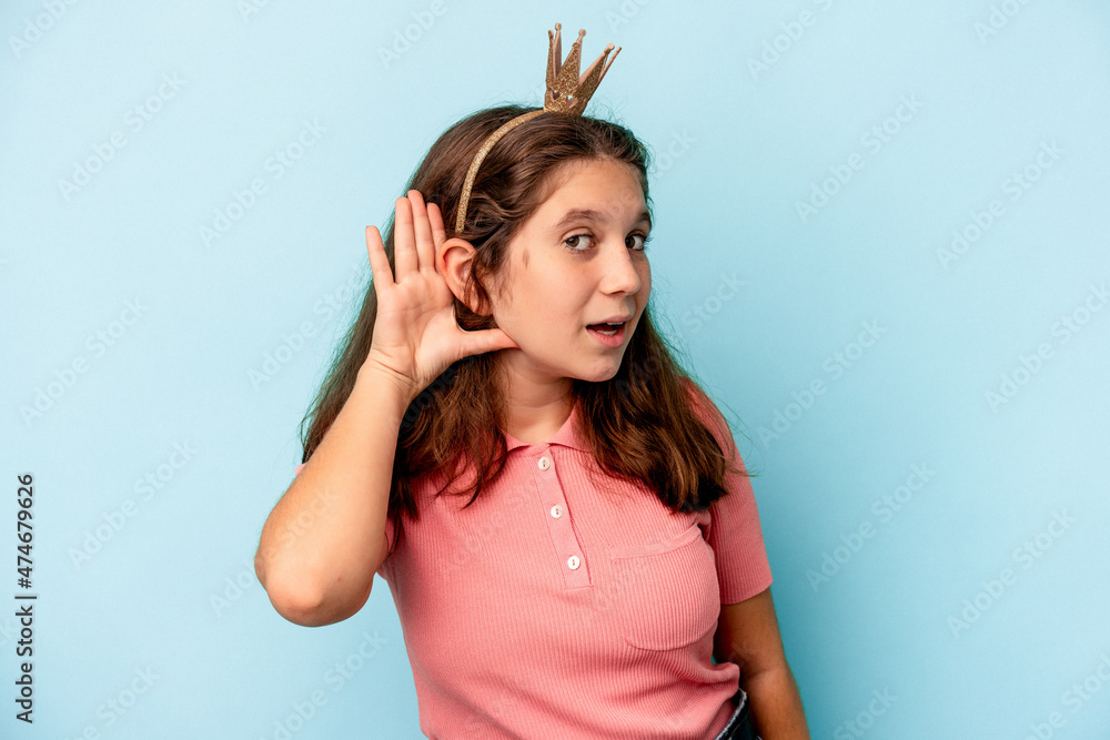 Little caucasian girl wearing a princess crown isolated on blue background trying to listening a gossip. Little caucasian girl wearing a princess crown isolated on blue background trying to listening a gossip.