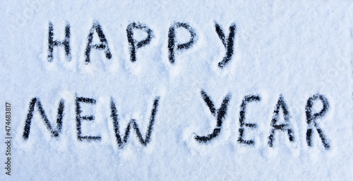 Happy New Year words written on the surface of a snow field.