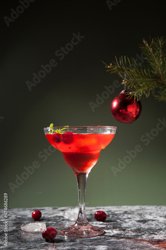 Drink with cranberries and alcohol in a conical glass on a concrete surface