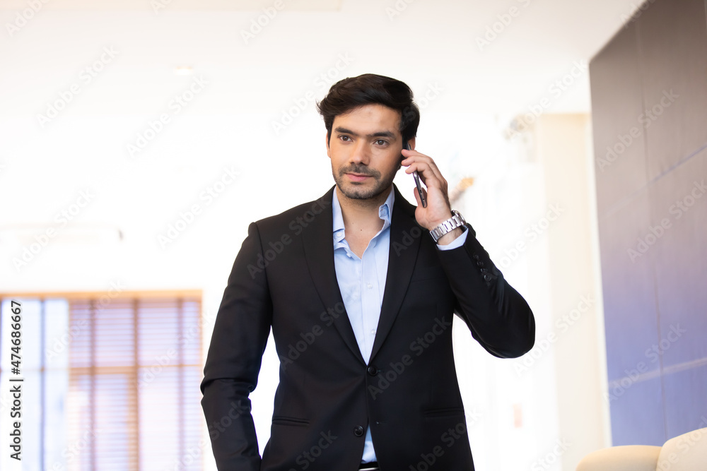 portrait young confident business man at the office. Businessman using mobile phone.