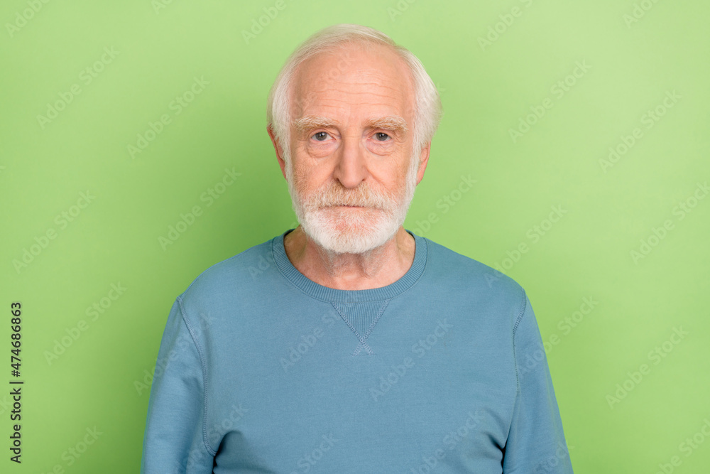 Photo of strict elder beard man wear blue sweater isolated on green color background Photo of strict elder beard man wear blue sweater isolated on green color background
