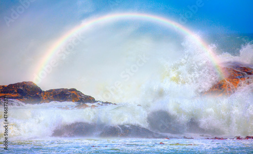 Long strong sea waves with rainbow reflection on a windy day