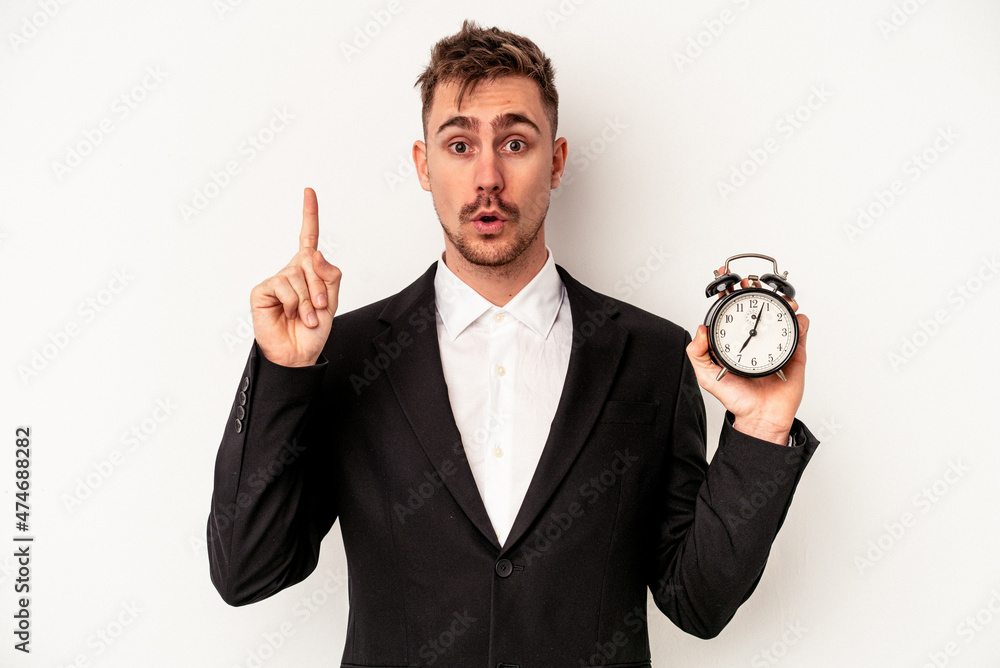 Young caucasian business man holding alarm clock isolated on white background having some great idea, concept of creativity. Young caucasian business man holding alarm clock isolated on white background having some great idea, concept of creativity.