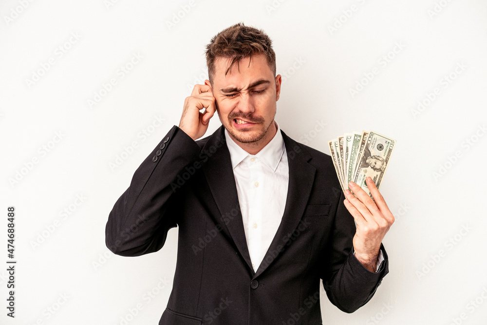 Young caucasian business man holding bank notes isolated on white background covering ears with hands. Young caucasian business man holding bank notes isolated on white background covering ears with hands.