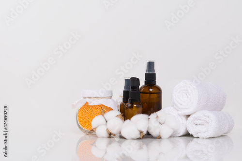 on a white background, rolled towels, aromatic oils for massage and yellow bath salt in a glass jar, there is a place for the inscription