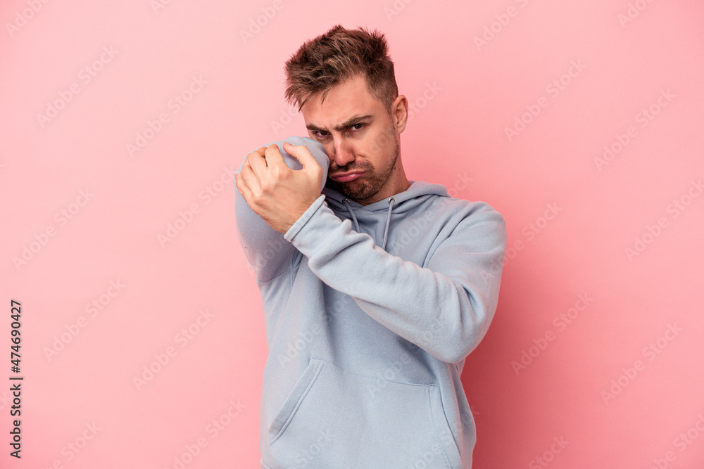 Young caucasian man isolated on pink background having a neck pain due to stress, massaging and touching it with hand. Young caucasian man isolated on pink background having a neck pain due to stress, massaging and touching it with hand.