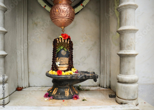 Fotografie A Close up picture of a Shiva Lingam made of stone material with a brass vessel to anoint milk to the deity at a Hindu temple during Shivratri in India