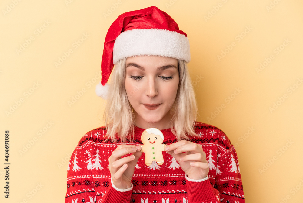 Young caucasian woman holding Christmas cookies isolated on yellow background Young caucasian woman holding Christmas cookies isolated on yellow background