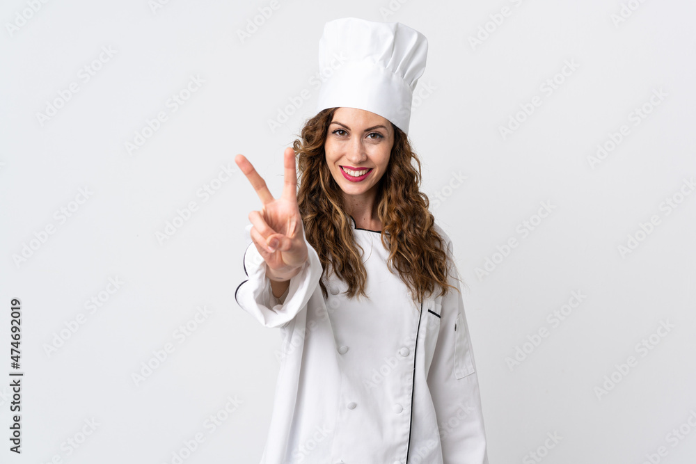Young chef woman isolated on white background smiling and showing victory sign Young chef woman isolated on white background smiling and showing victory sign