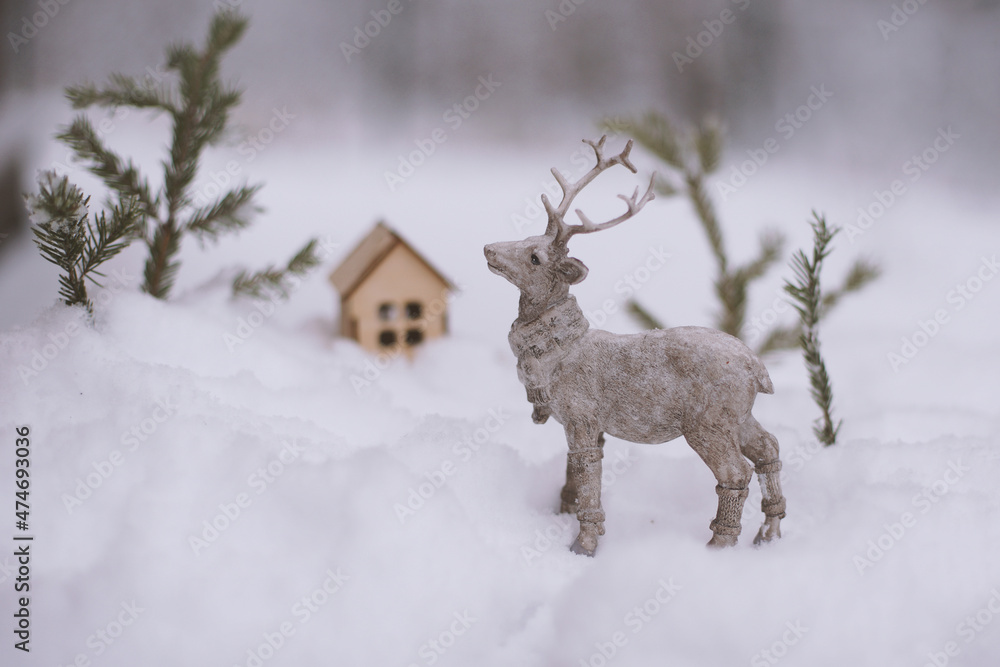 The figure of a deer, toy houses, fir branches in the snow. The figure of a deer, toy houses, fir branches in the snow.