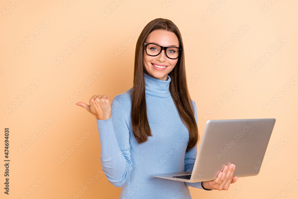 Photo of smart brunette young lady hold laptop index promo wear spectacles blue turtleneck isolated on beige color background Photo of smart brunette young lady hold laptop index promo wear spectacles blue turtleneck isolated on beige color background
