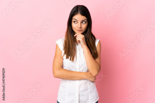 Young caucasian woman isolated on pink background having doubts and thinking