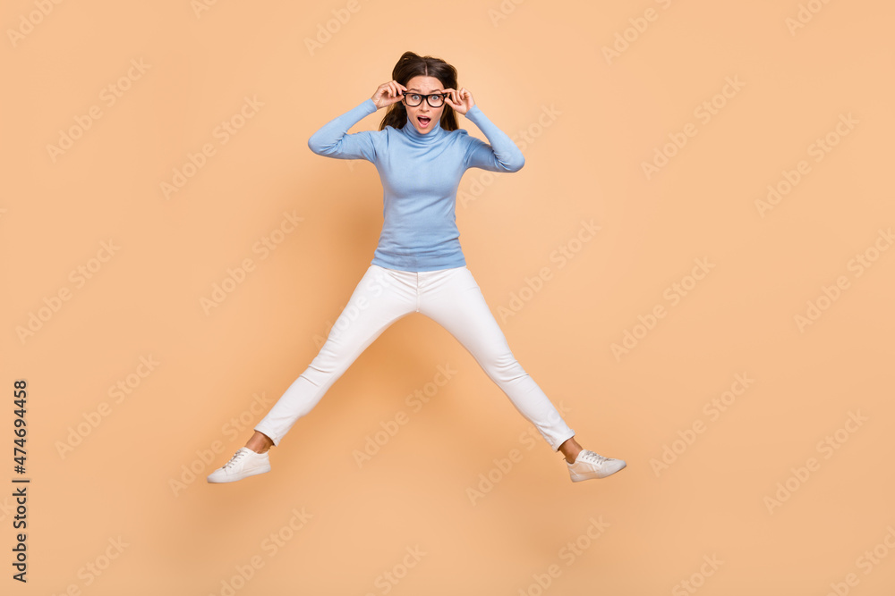 Full size photo of impressed young lady jump wear eyewear sweater pants shoes isolated on beige background Full size photo of impressed young lady jump wear eyewear sweater pants shoes isolated on beige background