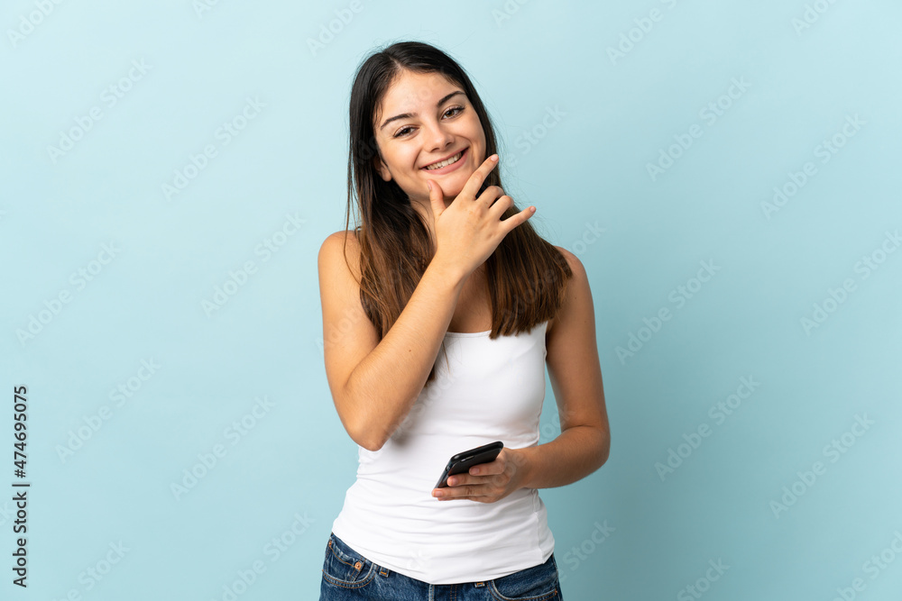 Young caucasian woman using mobile phone isolated on blue background happy and smiling Young caucasian woman using mobile phone isolated on blue background happy and smiling