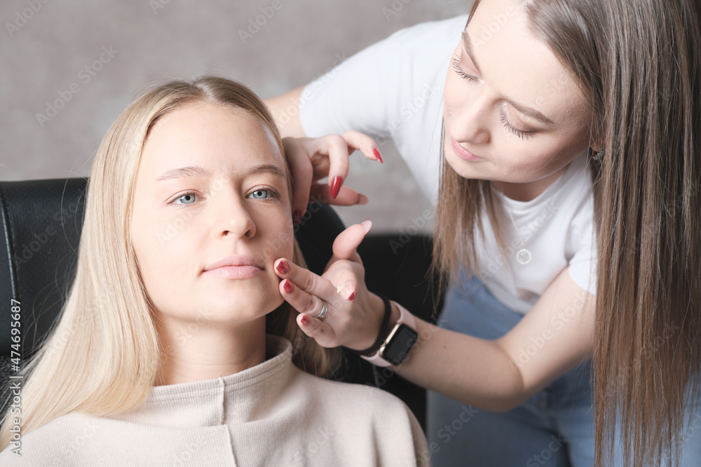 visagiste or make-up artist using fingers to apply CC cream on young woman's face. blond beautiful woman in beauty studio visagiste or make-up artist using fingers to apply CC cream on young woman's face. blond beautiful woman in beauty studio