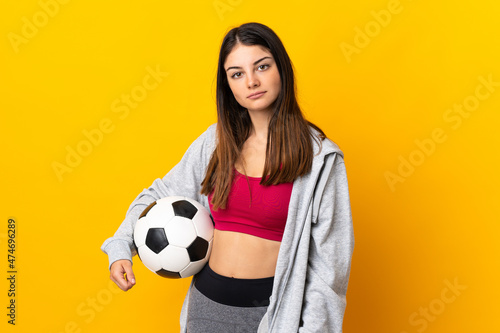 Young caucasian woman isolated on yellow background with soccer ball © luismolinero