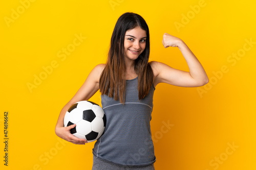 Young football player woman isolated on yellow background doing strong gesture © luismolinero