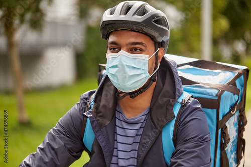 food shipping, health and pandemic concept - delivery man in bicycle helmet and protective medical mask with thermal insulated bag on city street