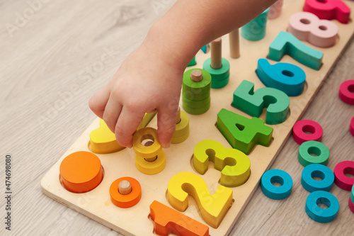 The child is playing with a colorful wooden educational toy.