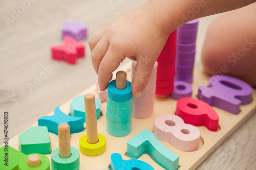 The child is playing with a colorful wooden educational toy.