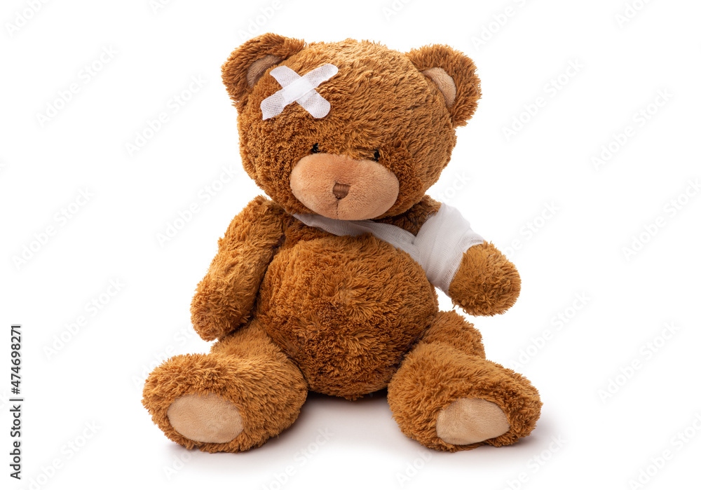 medicine, healthcare and childhood concept - teddy bear toy with bandaged paw and patch on head on white background