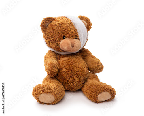 medicine, healthcare and childhood concept - teddy bear toy with bandaged head having toothache on white background