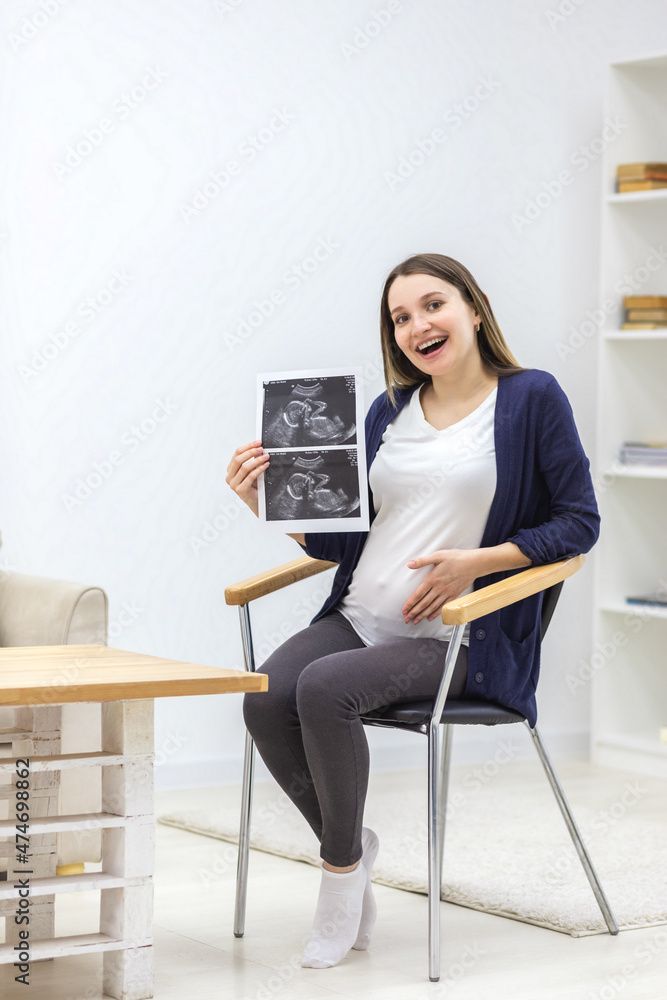 Photo of smiling pregnant woman holding ultrasound result. Photo of smiling pregnant woman holding ultrasound result.