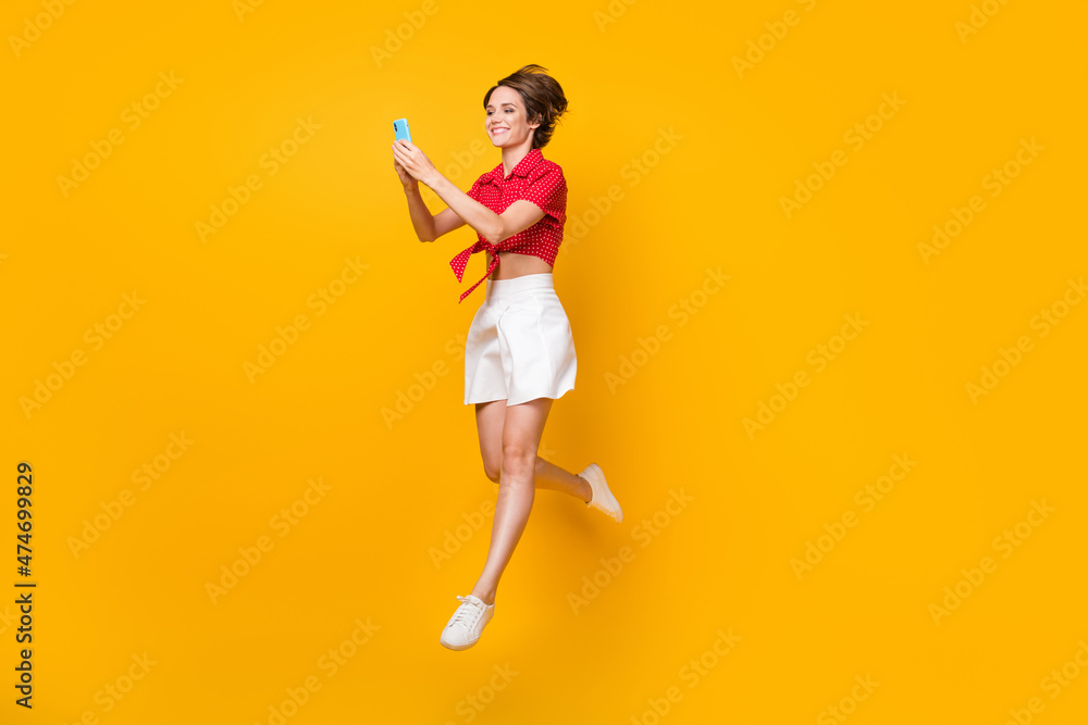 Full length profile photo of attractive cheerful lady beaming smile typing blog post isolated on yellow color background Full length profile photo of attractive cheerful lady beaming smile typing blog post isolated on yellow color background