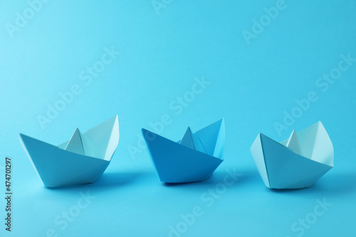 Handmade paper boats on light blue background. Origami art