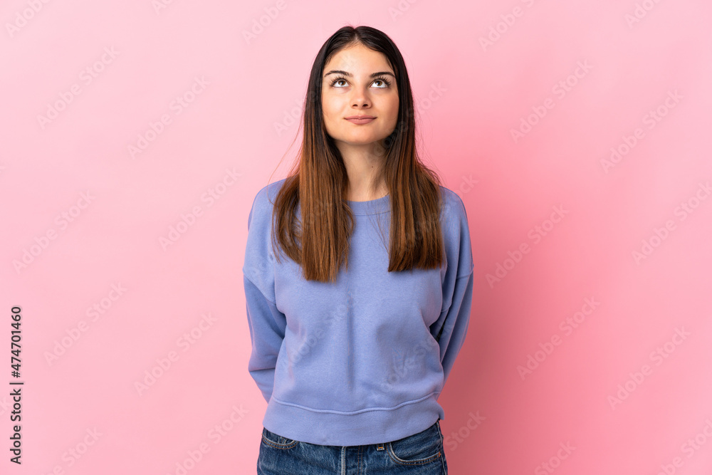 Young caucasian woman isolated on pink background and looking up Young caucasian woman isolated on pink background and looking up