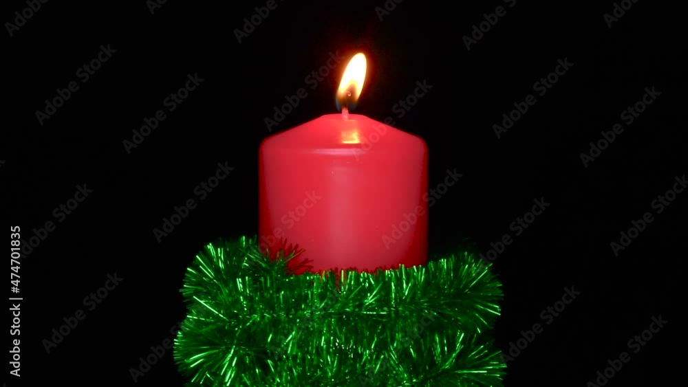 Decorated with green rain rotates candle on a black background close-up Decorated with green rain rotates candle on a black background close-up